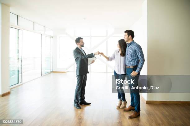 Couple Getting Keys From Real Estate Agent Of Their New Home Stock Photo - Download Image Now