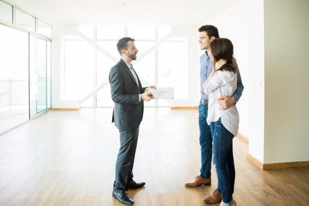 istock Broker Discussing With Couple While Standing In New House 1023536742