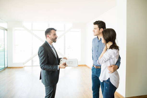 Confident Agent Showing New Apartment Plan To Couple