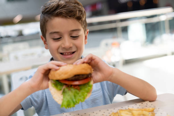 istock Beautiful little boy enjoying a delicious burger 1023542396