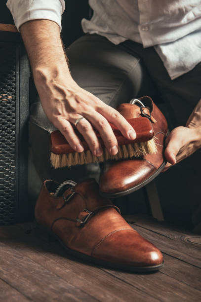 Bootblack cleans brown monk shoes with a brush and shoe polish stock photo