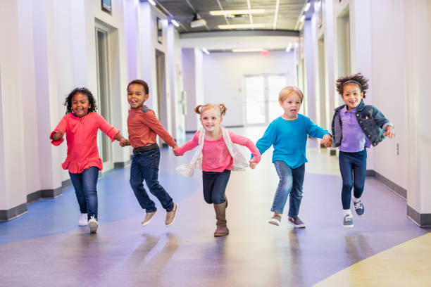 dzieci w wieku przedszkolnym trzymające się za ręce biegnące korytarzem - preschool child preschooler multi ethnic group zdjęcia i obrazy z banku zdjęć