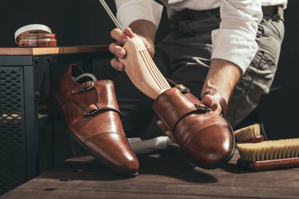 Bootblack prepares shoes for cleaning in his workshop stock photo