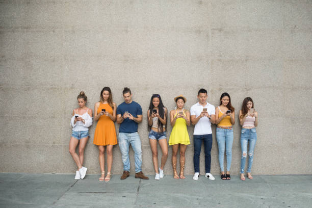 istock Young people leaning back on a wall and playing mobile games 1023545782