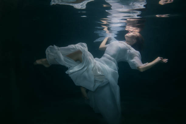 Woman under the water. Beautiful woman in a white dress swims under the water. drowning photos stock pictures, royalty-free photos & images