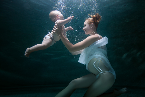 Mom trains an infant to dive under water.