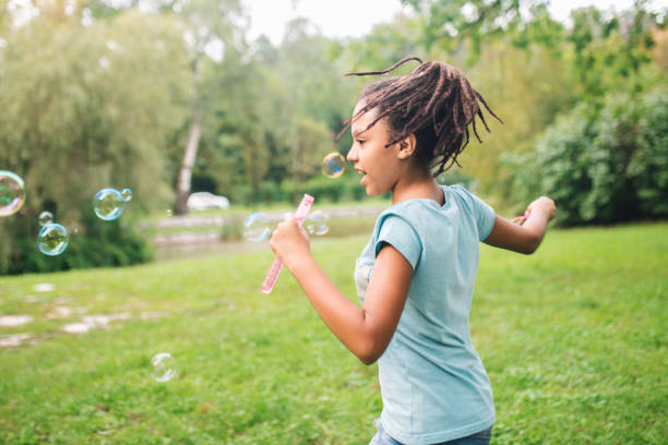 istock Young girl running in the park and making soap bubbles 1023551368