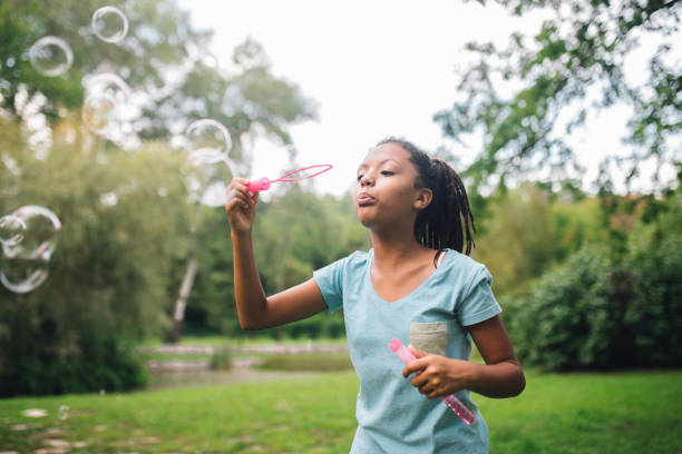 istock Young girl blowing soap bubbles at the park 1023551376