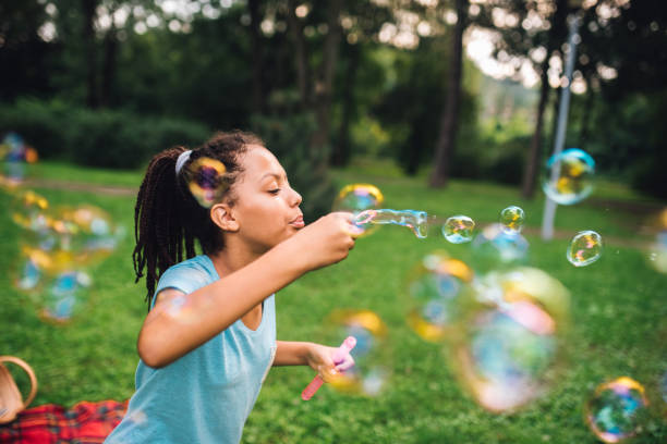 istock Young girl blowing at bubble wand 1023551612