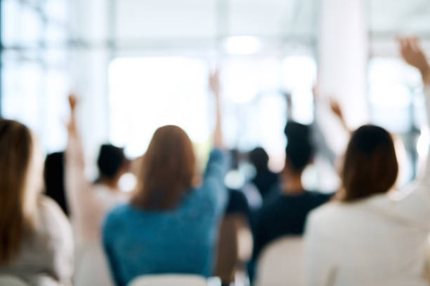 An interactive audience is an engaged audience Rearview shot of a group of businesspeople raising their hands to ask questions during a conference arms raised stock pictures, royalty-free photos & images