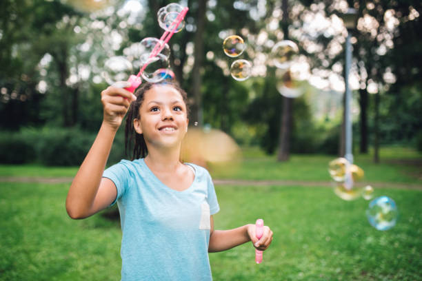 istock Cute young girl smiling and making soap bubbles with bubble wand 1023551966