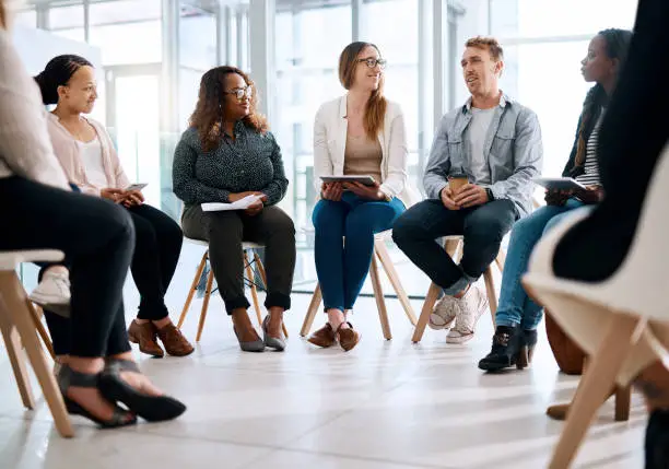 Shot of a group of businesspeople sitting in a circle and having a meeting in a modern office