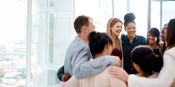 Shot of a group of young businesspeople huddled together in solidarity in a modern office