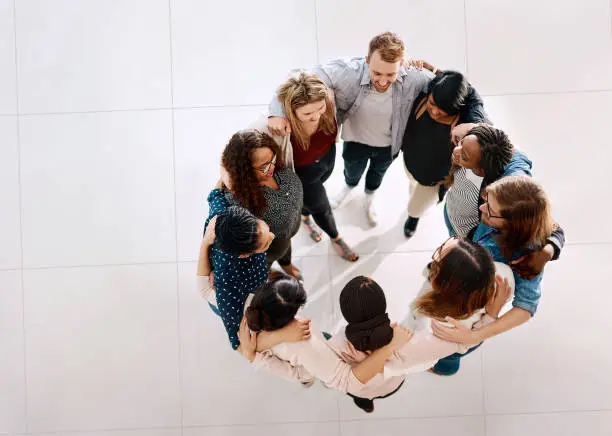 High angle shot of a group of young businesspeople huddled together in solidarity in a modern office