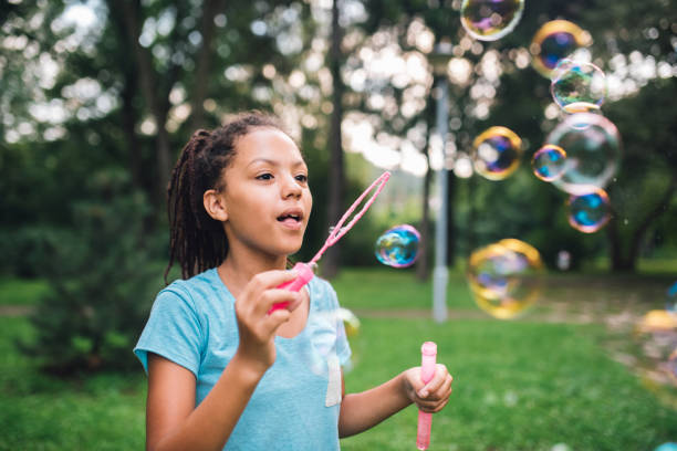 istock Girl looking at soap bubbles she just made with bubble wand 1023552092