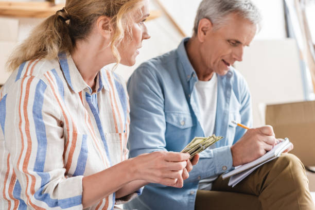istock elderly couple counting money and taking notes in notebook during relocation 1023552726