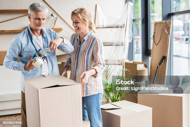 Happy Senior Couple Packing Cardboard Boxes During Relocation Stock Photo - Download Image Now
