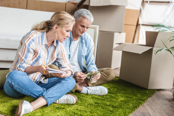 istock focused senior couple sitting on carpet and counting money during relocation 1023554558
