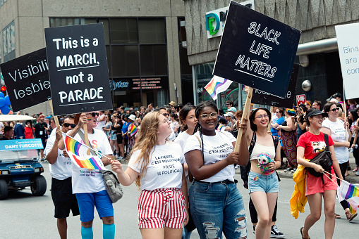 Group of people participating at the annual LGBTQ Pride parade in Montreal on Rene-Levesque boulevard. The sign remind us that people are marching for theirs rights, not for fun, and that in the LGBTQ community, black life matters.