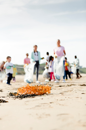 People on the beach collecting litter but not in focus as focus falls onto some fishing net on the sand in the foreground