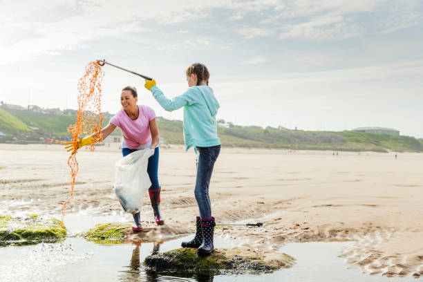 istock Females Collecting Plastics and Rubbish Off a Beach 1023573364