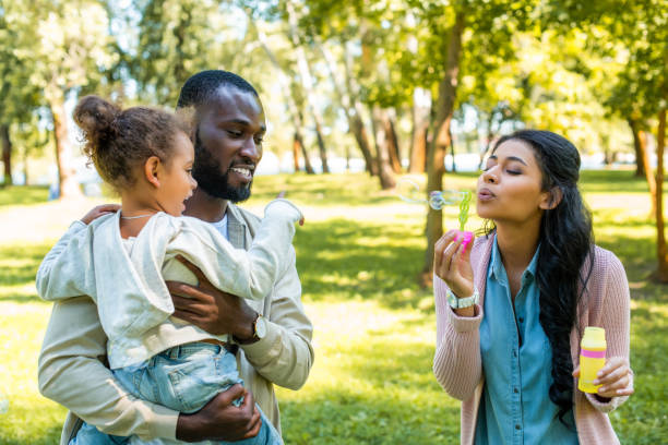 istock african american mother blowing soap bubbles in park 1023579222