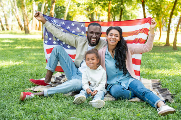uśmiechnięty afroamerykańskich rodziców i córki gospodarstwa amerykańskiej flagi na pikniku w parku - preschooler child offspring purity zdjęcia i obrazy z banku zdjęć