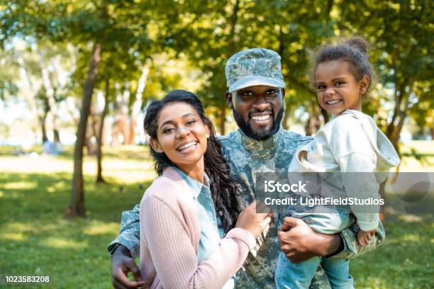Photo libre de droit de Joyeux Soldat Afroaméricain En Militaire Uniforme Regardant Caméra Avec La Famille Dans Le Parc banque d'images et plus d'images libres de droit de Armée