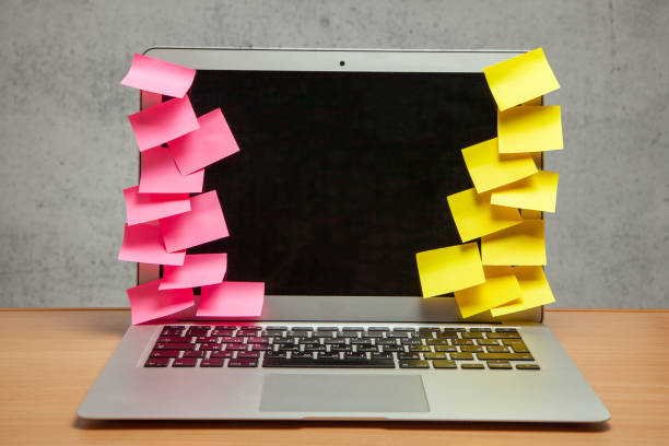 istock Laptop in reminders with yellow and red stickers notes on the display frame on table with gray wall 1023583630