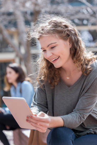 istock Young woman uses her e-reader while on a bench in the park 1023588282