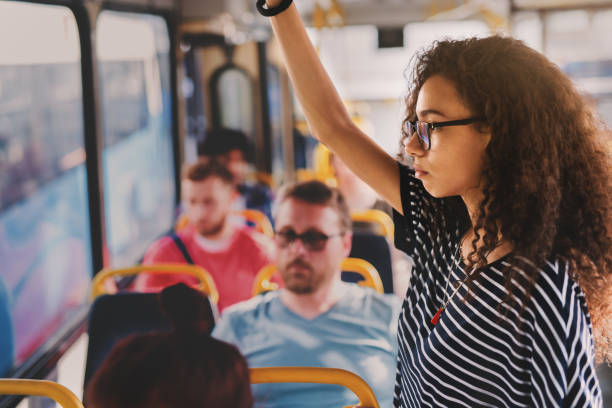 sérieuse jeune fille bouclée debout dans un bus plein de gens. - subway station railroad station netherlands subway photos et images de collection