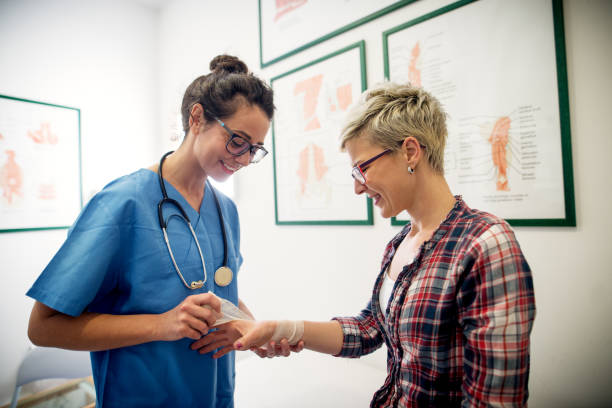 Professional carry medical nurse putting a bandage on a young girls injured hand. Professional carry medical nurse putting a bandage on a young girls injured hand. sports training clinic stock pictures, royalty-free photos & images