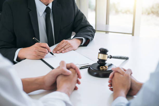 Agreement prepared by lawyer signing decree of divorce (dissolution or cancellation) of marriage, husband and wife during divorce process with male lawyer or counselor and signing of divorce contract stock photo