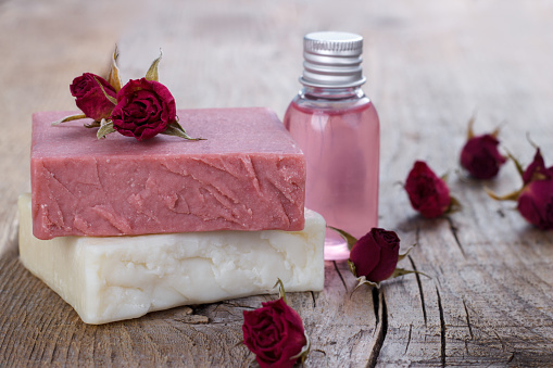 Natural hand made soap with dry pink roses on vintage wooden background spa setting