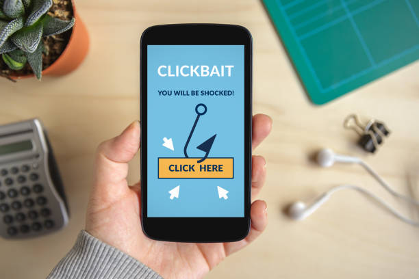 Hand holding smart phone with clickbait concept on screen stock photo