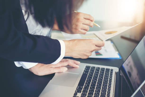 istock Asian businesswomen holding a pen and analysis documents on office table with laptop computer and graph financial diagram working in the background 1023611966