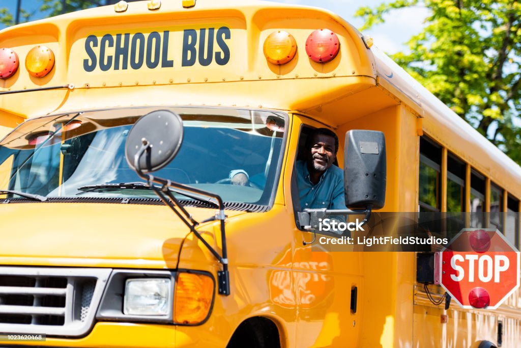 handsome senior school bus driver looking at camera through window School Bus Stock Photo