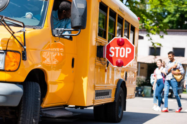 istock senior school bus driver looking at teens walking behind bus 1023620498