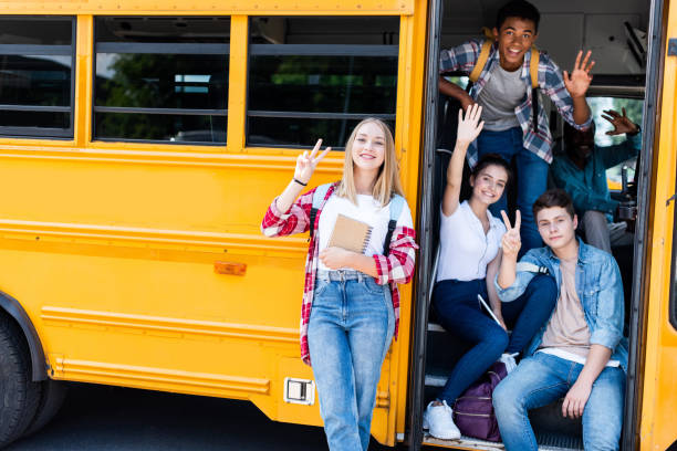 group of teen scholars sitting at school bus with driver inside and showing various gestures at camera group of teen scholars sitting at school bus with driver inside and showing various gestures at camera back to school teens stock pictures, royalty-free photos & images