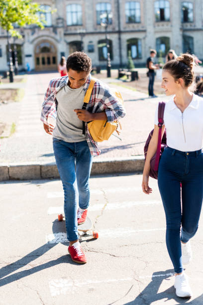 istock teen students walking at college garden with skateboard 1023622708