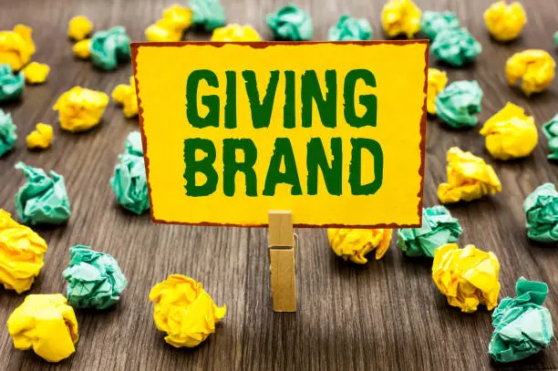 Photo of Conceptual hand writing showing Giving Brand. Business photo text The process of giving a Name to a company products or services Clothespin holding yellow note paper crumpled papers mistakes