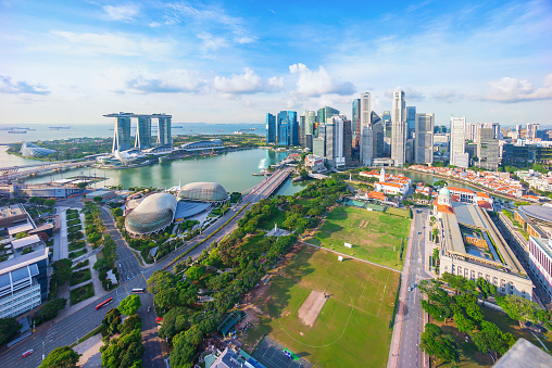 Singapore Urban Cityscape - Skyline at Marina Bay in colorful twilight after sunset. Drone Point of view panorama. Stitched Panorama DJI Mavic 3 Pro. View over the glowing Singapore Waterfront Modern Skyscrapers and light reflexions under moody twilight skyscape. Singapore, Southeast Asia, Asia