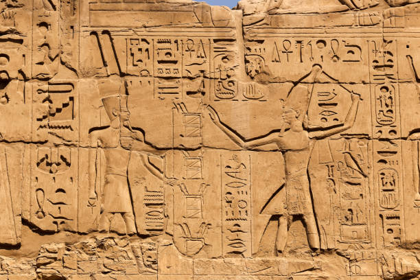 istock stone wall with Egyptian carving figures and hieroglyphs, Luxor, Egypt. 1023629498