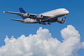 Airplane Airbus A380 flying between clouds before landing
