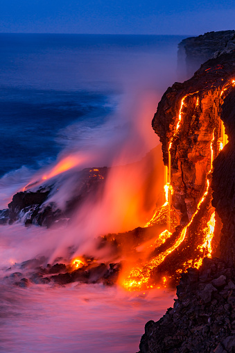Lava falls over the cliff into the ocean at Kilauea