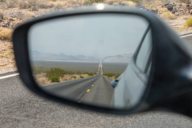 Rear View Mirror Looking into the rear view mirror of a car, at a long, straight road in Death Valley, California death valley desert photos stock pictures, royalty-free photos & images
