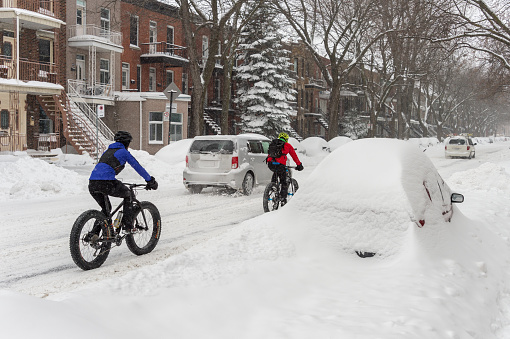 Montreal, CANADA - 13 January 2018: Two men are riding bikes during snowstorm