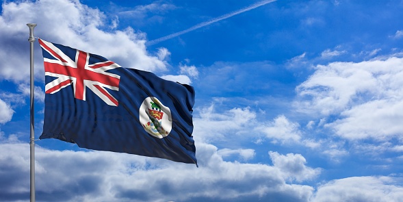 Cayman Islands flag waving on a blue sky background. 3d illustration