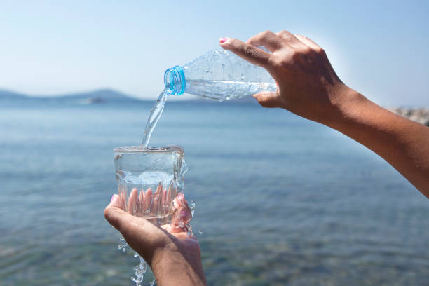istock The hand is pouring water from the bottle on the beach. 1023735442