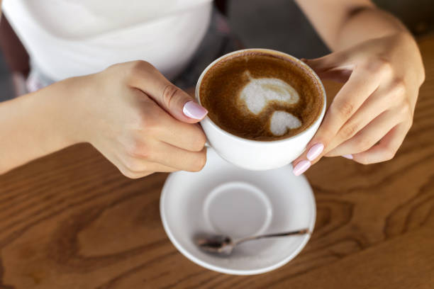 istock Woman holding coffee cup with foam art 1023738144